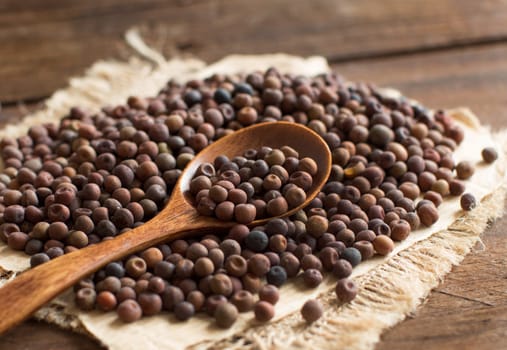 Raw organic roveja beans with a spoon on a wooden table