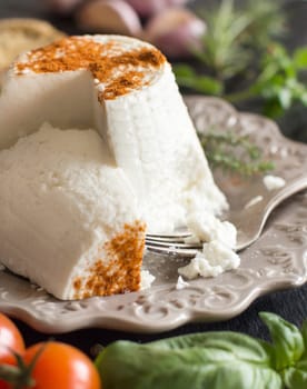 Italian ricotta cheese, vegetables and herbs on a dark background