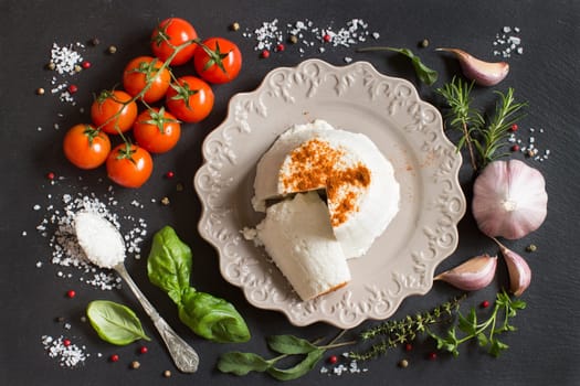 Italian ricotta cheese, vegetables and herbs on a dark background