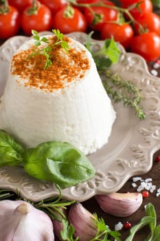 Italian ricotta cheese, vegetables and herbs on a wooden background