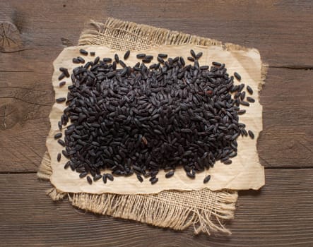 A pile of black rice on a wooden table top view