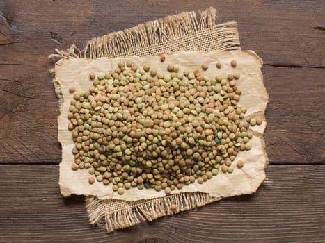 Pile of green lentils on a wooden table top view