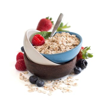 Rolled oats in a bowl with berries isolated on white