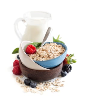 Rolled oats in a bowl with berries and milk isolated on white