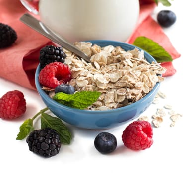 Rolled oats in a bowl with berries and milk isolated on white