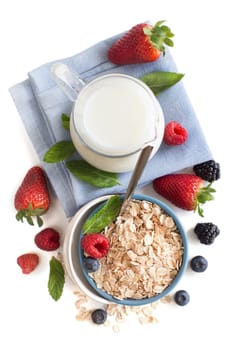 Rolled oats in a bowl with berries and milk isolated on white