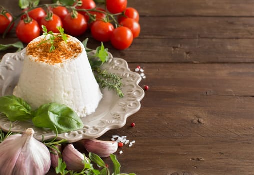 Italian ricotta cheese, vegetables and herbs on a wooden background