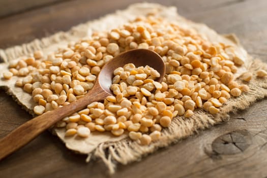 Pile of dried yellow peas with a spoon on a table