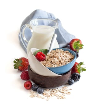 Rolled oats in a bowl with berries and milk isolated on white