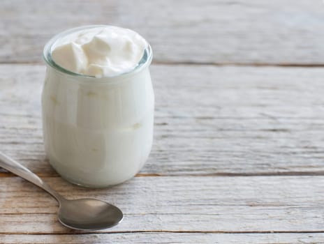 Jar of fresh greek yogurt on a wooden table