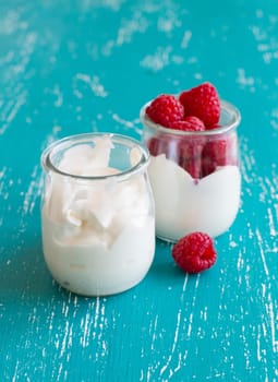 Raspberries and fresh yogurt in a jar on a turquoise background
