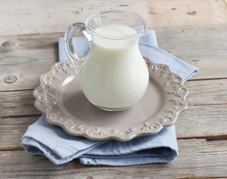Milk in a jar on a napkin on a wooden table