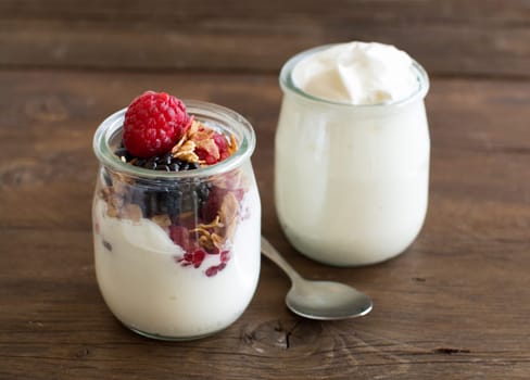 Berries, flakes and fresh greek yogurt on a wooden table