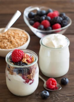 Berries, flakes and fresh greek yogurt on a wooden table