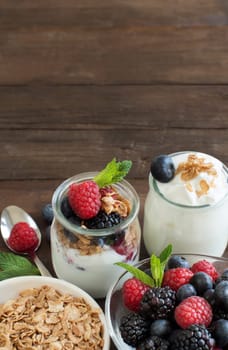 Berries, flakes and fresh greek yogurt on a wooden table