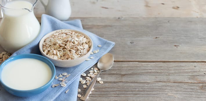 Rolled oats in a bowl and milk on a wooden table