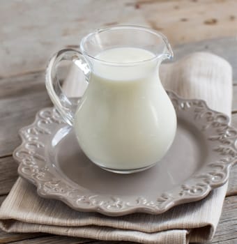Milk in a jar on a napkin on a wooden table