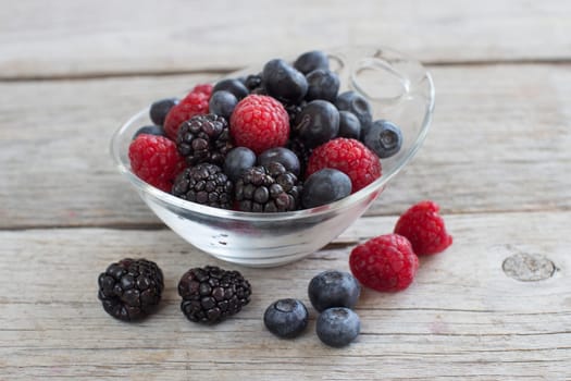Fresh berries in a bowl on the wooden table