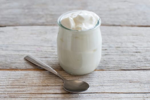 Jar of fresh greek yogurt on a wooden table