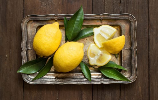 Fresh lemons on a tray on a wooden table