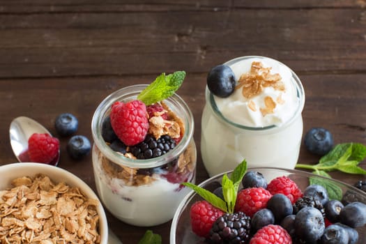 Berries, flakes and fresh greek yogurt on a wooden table
