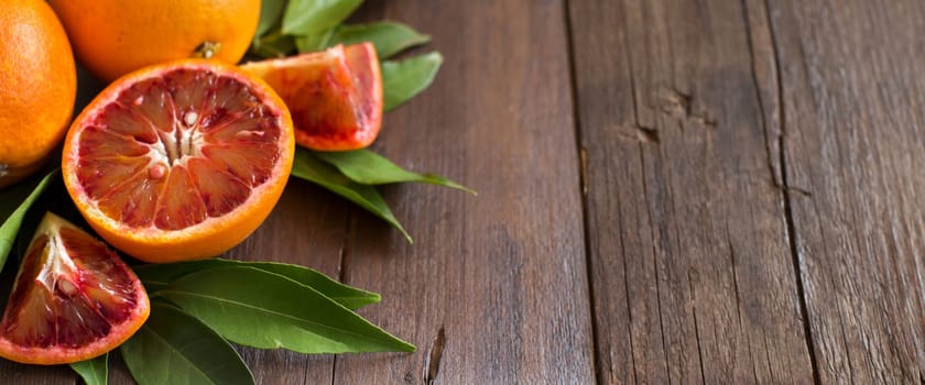 Fresh red Sicilian oranges with leaves on a wooden table