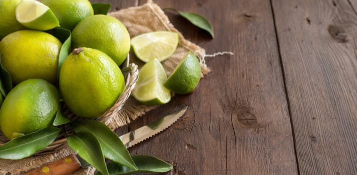 Fresh limes with knife on a wooden table