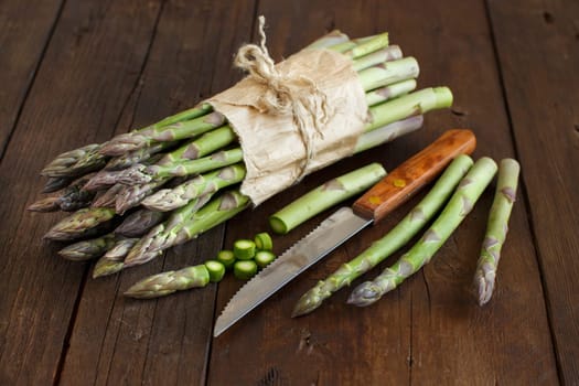 Fresh asparagus spears with knife on a wooden table