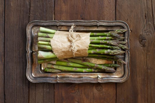 Bundle of fresh asparagus spears on a metal tray