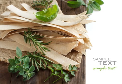 Wholegrain artisan pasta and herbs on old wooden table