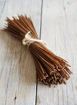 Brown rye spaghetti on the old wooden table