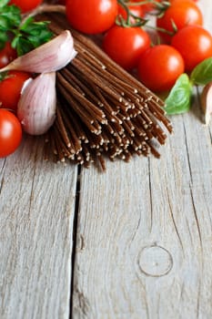 Wholegrain rye spaghetti, tomatoes and herbs on wood
