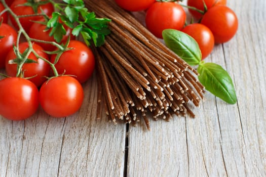Wholegrain rye spaghetti, tomatoes and herbs on wood