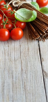 Wholegrain rye spaghetti, tomatoes and herbs on wood