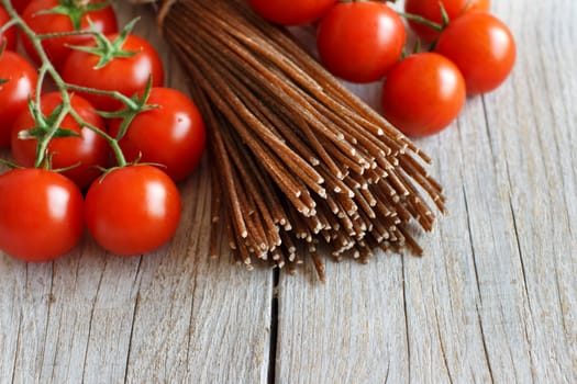 Wholegrain rye spaghetti, tomatoes and herbs on wood