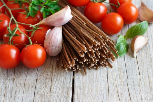 Wholegrain rye spaghetti, tomatoes and herbs on wood