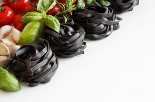 Black Tagliatelle pasta with cherry tomatoes, garlic and herbs on wood