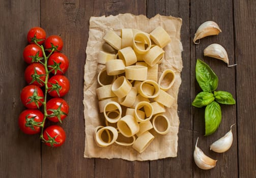 Pasta with garlic, tomatoes and basil on wooden background