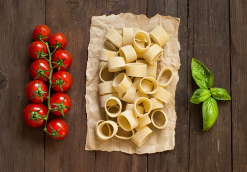 Pasta with tomatoes and basil on wooden background