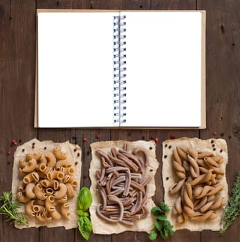 Whole wheat pasta and herbs on a wooden background