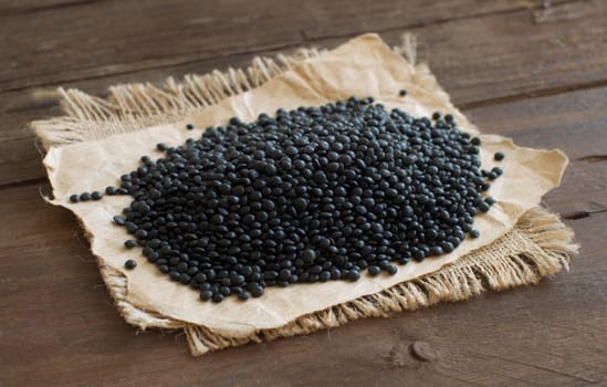Pile of Black Lentils on wood close up