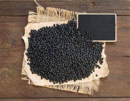 Pile of Black Lentils with a small chalkboard top view