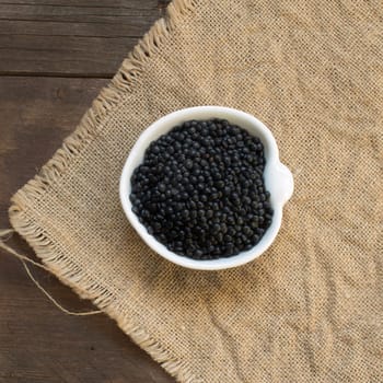 Black lentils in a bowl on a wooden table