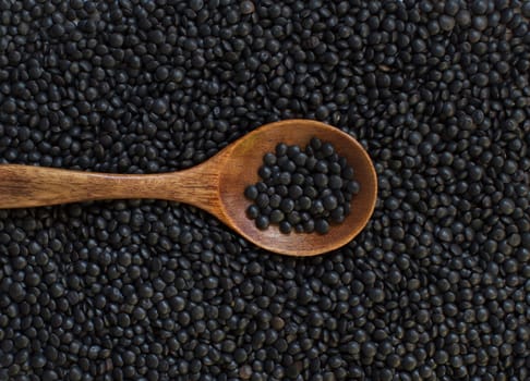 Pile of Black Lentils with a spoon top view