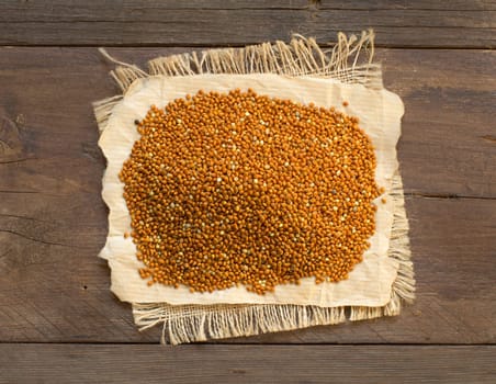 Pile of whole brown millet on a wooden table