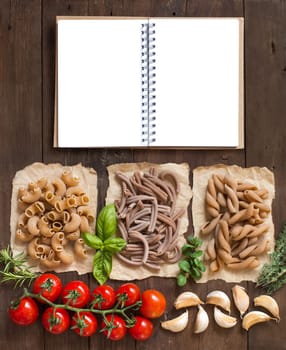 Whole wheat pasta with herbs and vegetables on a wooden background