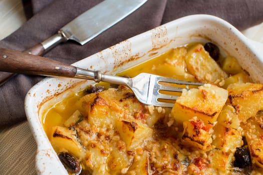 Fish with potatoes and olives cooked in oven in small casserole