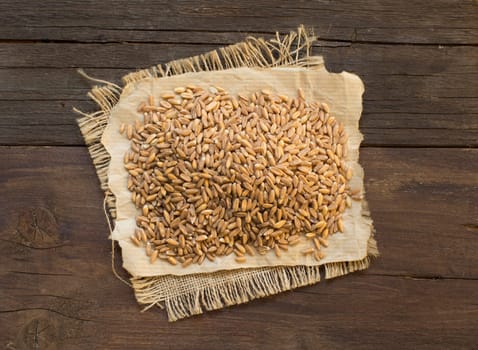 Pile of whole unpolished spelt on wooden table