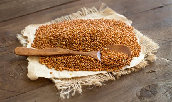 Whole brown millet pile with a spoon close up