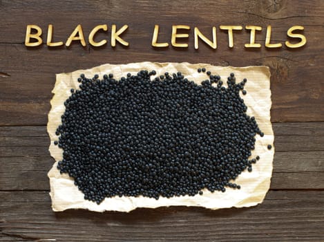 Pile of Black Lentils with a wooden word top view